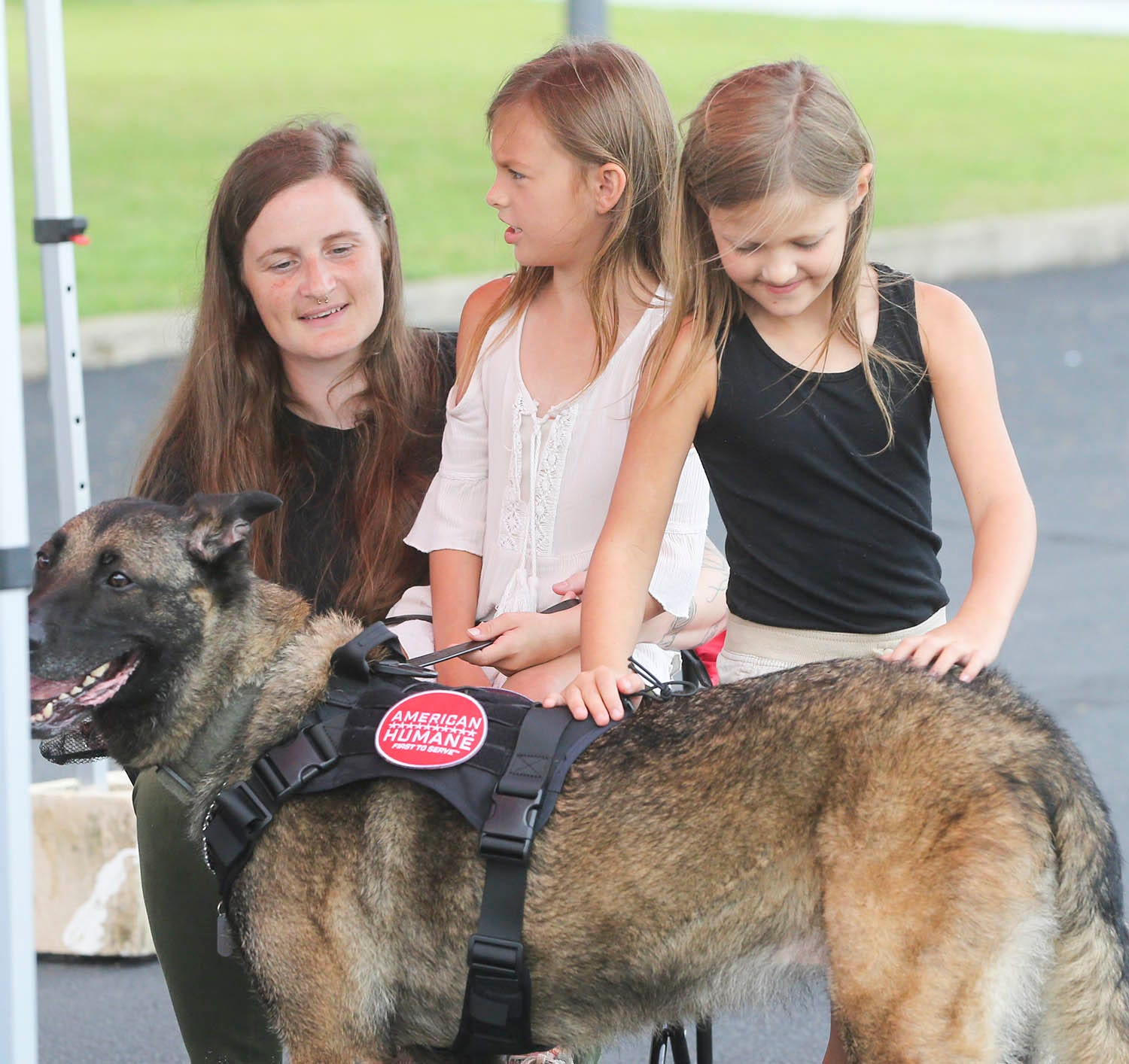 Staff Sgt. Porschia Allio-Easom, with daughters Shaylee and Ruby, gives attention to retired military dog Luna in a reunion event at the Eglin Federal Credit Union on Eglin Parkway in Fort Walton Beach.